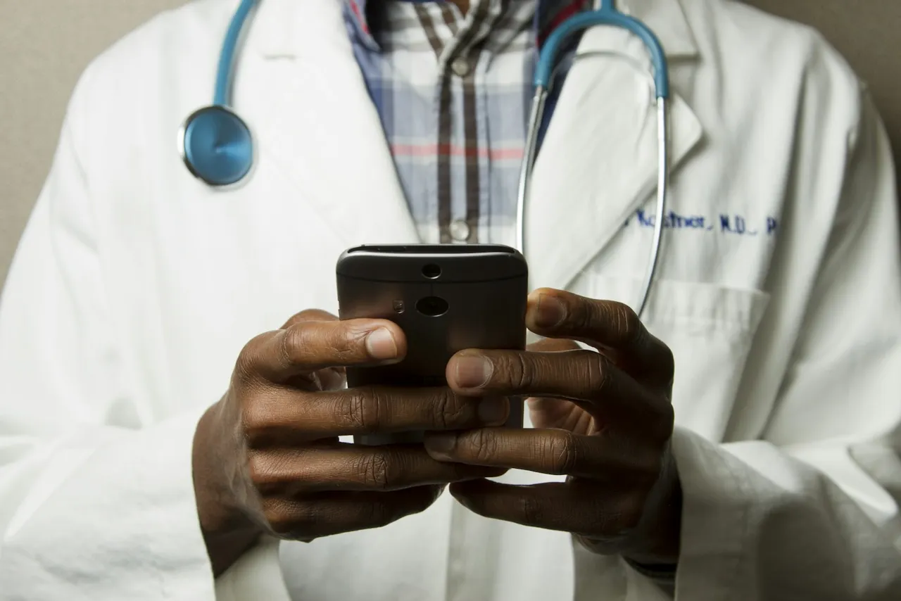 Healthcare professional with a stethoscope holding a phone